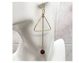 3 inch long earrings comprised of a gold wire triangl, a long gold chain and a garnet bead.